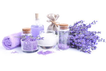 Obraz na płótnie Canvas Spa composition with flowers of lavender, cream, salt and bottle of essential oil on a white background