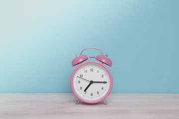 Retro alarm clock isolated on wooden table , Vintage style pastel color background