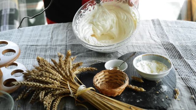 Closeup woman whip cream in glass bowl by mixer for tarts