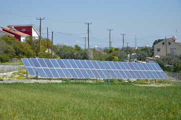 Solar panels on green field near houses  in Cyprus. Renewable alternative energy