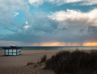 Fototapeta na wymiar beach hut at sunset with storm on the horizon