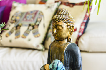 Statue of contemplating Buddha inside a modern, trendy house with eastern interior design...