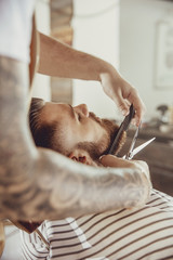 Barber cuts the client's beard with scissors and a comb. Photo in vintage style