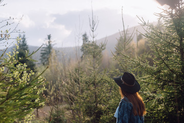 woman-traveler, looking at the amazing mountains and the forest, the concept of travelers travel, the place for the text, the atmospheric epic moment