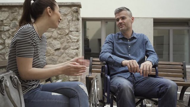 Man in wheelchair and his friend meeting and talking