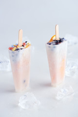 close-up view of sweet homemade popsicles with fruits and berries and ice cubes on grey