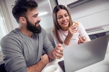 Happy young couple using laptop in kitchen