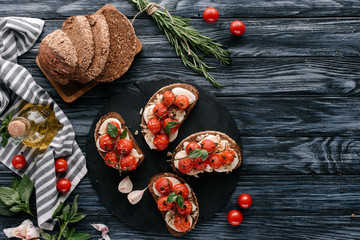 Multigrain bread with mozzarella and baked tomatoes on on dark slate board