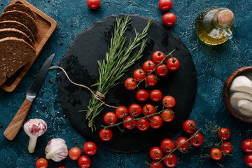 Red tomatoes with herbs and bread on dark blue table