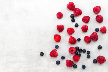 blueberries and raspberries on a gray background with a copy space