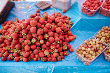 Gooseberry and strawberry on a farm market in the city. Fruits and vegetables at a farmers summer market.