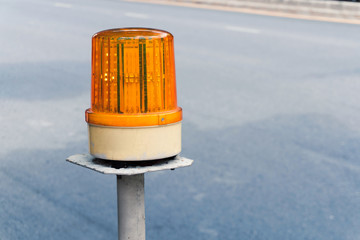 close up of a yellow LED warning light on the white metal pole beside the street