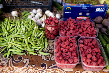 Raspberries, garlic and peas on a farm market in the city. Fruits and vegetables at a farmers summer market.