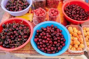 Sweet cherry, raspbeery and apricot on a farm market in the city. Fruits and vegetables at a farmers market. Cherries in boxes and trays