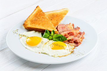 Tasty English breakfast with fried eggs, bacon and toasts on the