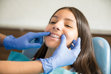 Girl With Braces Being Examined By Dentist In Clinic