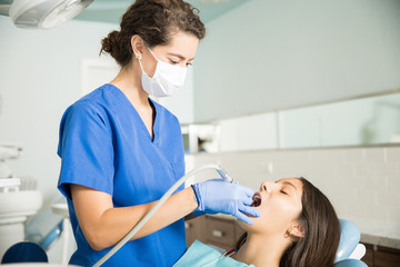 Dentist Examining Teenage Girl With Equipment At Clinic