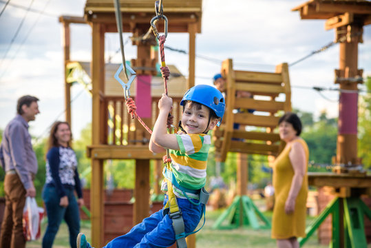 Adorable little boy enjoying his time in a rope playground structure at adventure park,