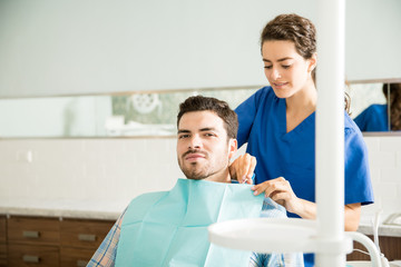 Dentist Preparing Man For Dental Treatment At Clinic