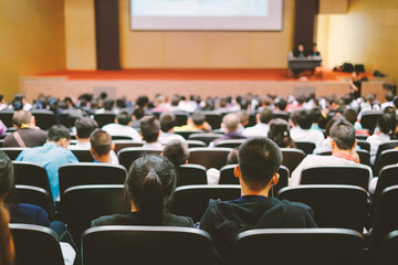 Education Conference and Presentation Audience at the conference hall. Focus on unrecognizable people from rear. Vintage tone.