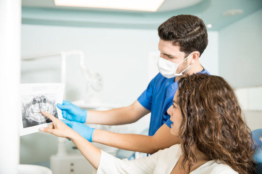 Dentist Showing Dental Xray To Female Patient In Clinic