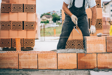 industrial construction site details with worker laying bricks