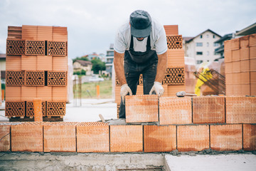 details of industrial bricklayer installing bricks on construction building site.