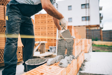 Close up of details of industrial bricklayer installing bricks on building construction site