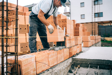 closeup of construction worker installing bricks, building house