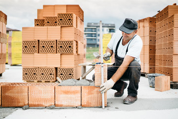 construction worker building walls and working with bricks on construction site