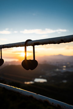 Love padlock hanging on fence in sunset