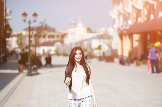 happy beautiful smiling girl walking on town street in sunny summer day