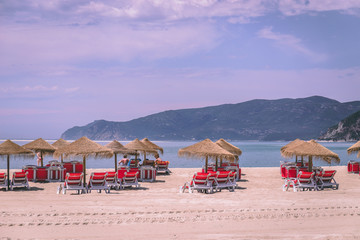Fototapeta premium Straw umbrellas and chairs at a sandy beach in Troia, Portugal