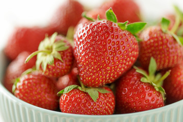 Fresh juicy strawberry in ceramic bowl close-up.