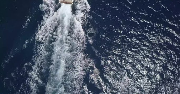 Aerial top view of yacht in Mykonos, Greece. Waves moving fast.
