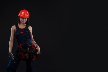 Obraz na płótnie Canvas Attractive young woman doing repairs at black background. Portrait of a female construction worker. Building, repair concept. Copy space