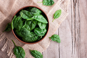 juicy spinach leaves in a bowl on a rustic wooden table. Top view. healthy food