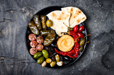 Middle Eastern meze platter with pita, olives, hummus, stuffed dolma, labneh cheese balls in spices. Mediterranean appetizer party idea