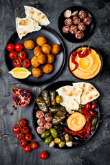 Arabic traditional cuisine. Middle Eastern meze platter with pita, olives, hummus, stuffed dolma, labneh cheese balls in spices. Mediterranean appetizer party idea