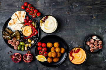Arabic traditional cuisine. Middle Eastern meze platter with pita, olives, hummus, stuffed dolma, labneh cheese balls in spices. Mediterranean appetizer party idea