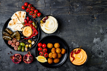 Arabic traditional cuisine. Middle Eastern meze platter with pita, olives, hummus, stuffed dolma, labneh cheese balls in spices. Mediterranean appetizer party idea