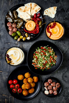 Arabic traditional cuisine. Middle Eastern meze platter with pita, olives, hummus, stuffed dolma, labneh cheese balls in spices. Mediterranean appetizer party idea