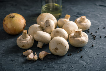 White Champions, spices and ingredients on the dark kitchen table. Concept of cooking mushroom dishes