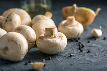 White Champions, spices and ingredients on the dark kitchen table. Concept of cooking mushroom dishes