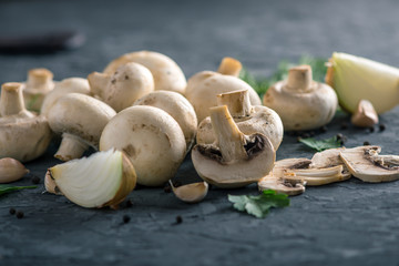 Fresh white Champions, green dill and ingredients on the dark kitchen table. Concept of cooking mushroom dishes