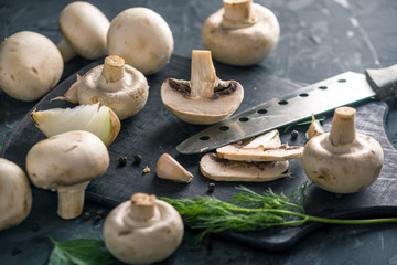White champignons cut in half with a knife and the ingredients. Concept of cooking mushroom dishes. Close up
