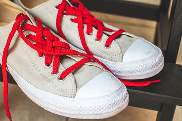 Pair of stylish beige sneakers with red laces 