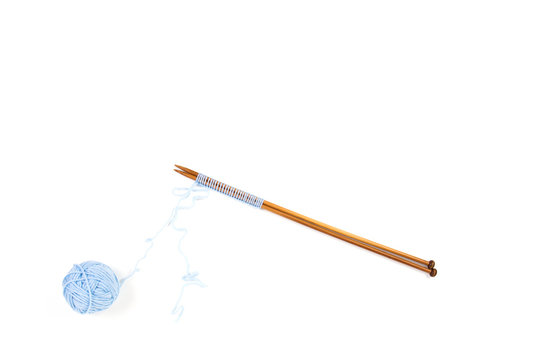 Knitting needles and blue yarn ball on white background