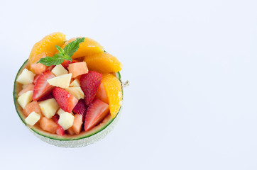 Melon stuffed with assorted fruits on white background. Flat lay.