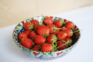 Red fresh strawberry in a colorful plate, on a white background.